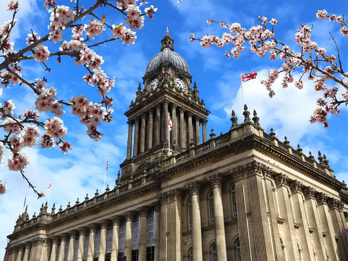 Historic building in Leeds, West Yorkshire, with cherry blossoms in the foreground and a bright blue sky.